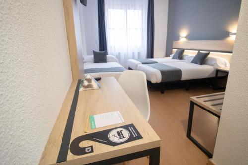 a hotel room with two beds and a table with a sign at Alda Puerto Seco in Burgos