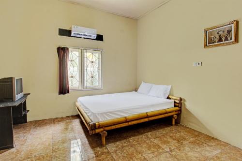 Habitación pequeña con cama y ventana en OYO 92197 Zahira Homestay, en Ekas