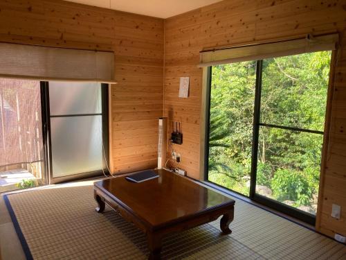uma sala de estar com uma mesa e uma grande janela em Eco Lodge Moss Tasha - Vacation STAY 39871v em Yakushima