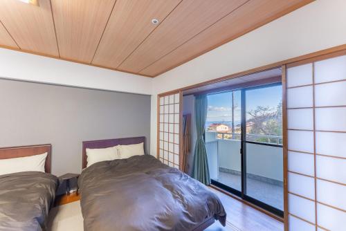 um quarto com 2 camas e uma grande janela em VIVI熱海 自然郷 3001丨VIVI Atami Shizenkyo 3001 em Atami