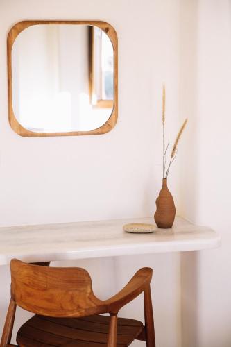 a mirror over a white table with a wooden chair at Ammothines Cycladic Suites in Naxos Chora