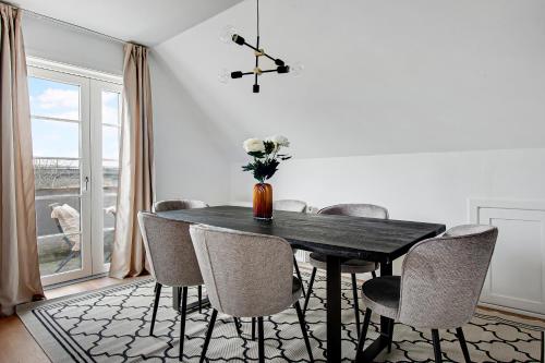 a dining room table with chairs and a vase with flowers at Charm 2 - Great 2-Bdr Apt with Shared Garden and Balcony in Copenhagen
