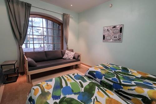 a bedroom with a bed and a couch and a window at Pinecrest Villa - Castle style living on seaside in Porvoo