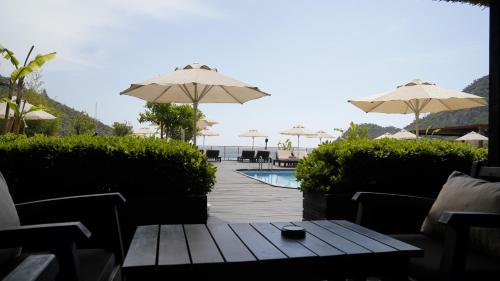 a patio with a table and umbrellas and a pool at Manaspark Deluxe Hotel in Oludeniz