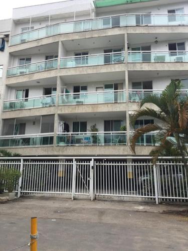 un edificio de apartamentos con una valla blanca y una palmera en brisa praiana, en Río de Janeiro