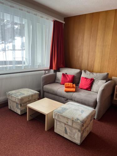a living room with a couch and two ottomans at Haus Atlantic Leukerbad in Leukerbad