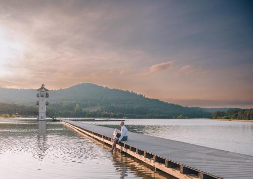 a man sitting on a dock in the water at Hotel Stronie in Stronie Śląskie