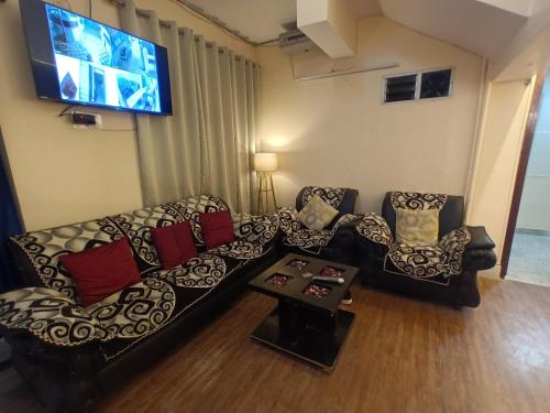a living room with two couches and a flat screen tv at The Clovers Inn Boring Road in Patna