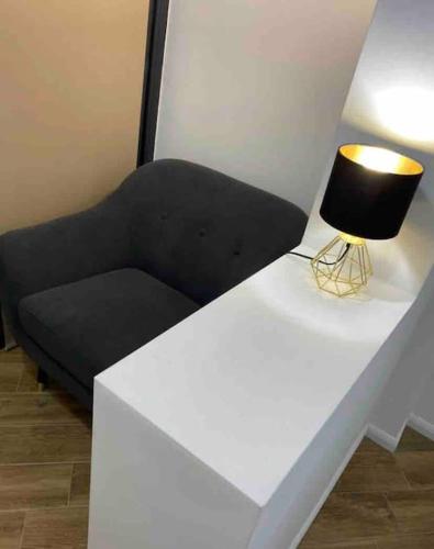 a black couch with a lamp on a white table at Enescu Flat in Suceava