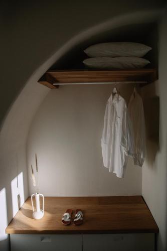 a wooden shelf with a white shirt and shoes on it at Ammothines Cycladic Suites in Naxos Chora