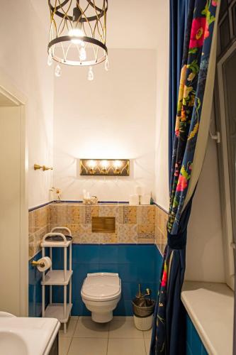 a bathroom with a toilet and a chandelier at Vila Rozalia Garden Gate in Avrig