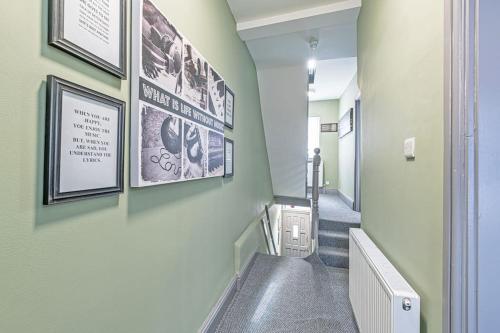 un couloir avec des escaliers et des photos sur le mur dans l'établissement Luxury 5 Bedroom Holiday Home Within Prescot, à Prescot