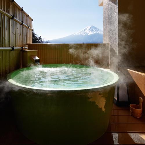 a hot tub with a mountain in the background at Fujikawaguchiko Onsen Konanso in Fujikawaguchiko