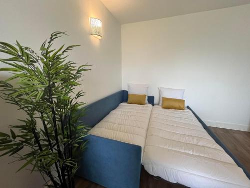 - 2 lits dans une chambre avec une plante dans l'établissement T2 Hyper Centre, proche port, plage et gare, au Pouliguen