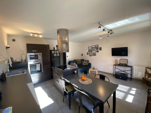 Il comprend une cuisine et un salon avec une table et une cuisinière. dans l'établissement Appartement douillet, proche gare, terrasse, cave, à Saint-Jean-de-Maurienne