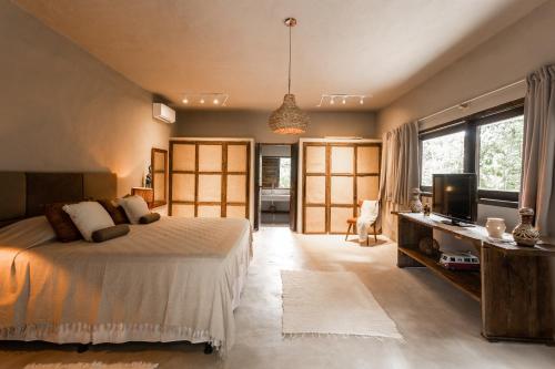 a bedroom with a bed and a desk with a television at CASA SUKHA Hotel in Trancoso