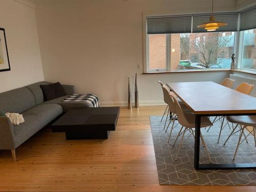 ein Wohnzimmer mit einem Sofa, einem Tisch und Stühlen in der Unterkunft Central lejlighed i Herning in Herning