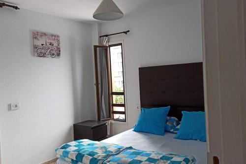 una camera da letto con un letto con cuscini blu e una finestra di Altemar in las Américas ad Arona