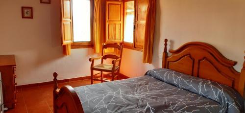 1 dormitorio con 1 cama, 1 silla y ventanas en El Portal, en Letur