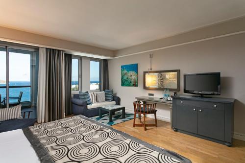 a hotel room with a bed and a desk and a television at Xanadu Island in Akyarlar