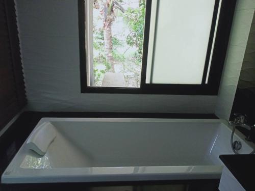 a white bath tub in a bathroom with a window at Boat House Boutique Riverside in Talat Amphoe Nakhon Chai Si