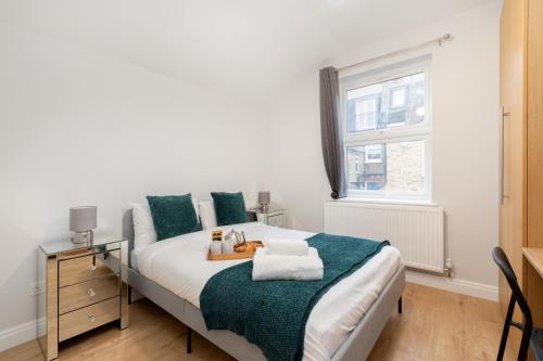 a bedroom with a bed with green and white sheets and a window at Spacious apartment near Hammersmith staion in London