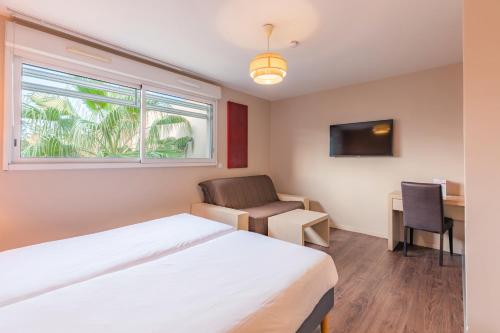 a bedroom with a bed and a chair and a window at Appart’City Confort Montpellier Ovalie I in Montpellier