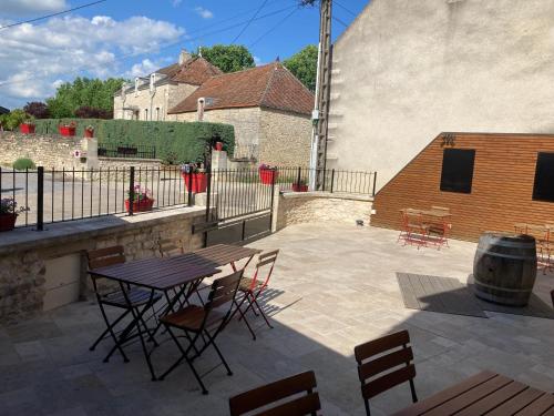 a patio with a table and chairs and a barrel at L'Aubergiste in Corcelles-les-Arts