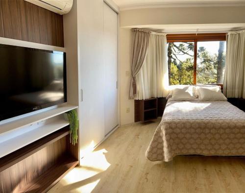 1 dormitorio con 1 cama y TV de pantalla plana en Lof Araucárias próx Rua Coberta by Achei Gramado, en Gramado