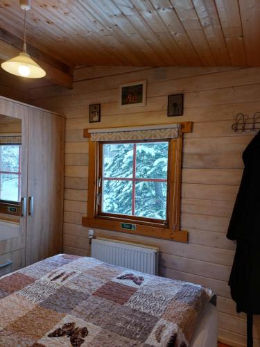 a bedroom with a bed and a window at Bakkakot 1 - Cozy Cabins in the Woods in Akureyri