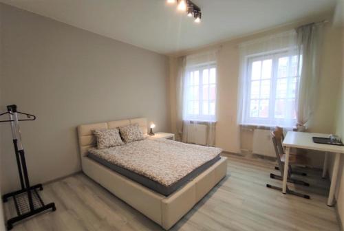 um quarto com uma cama, uma secretária e janelas em Rynek 9 em Poznań