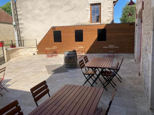 a patio with tables and chairs and a barrel at L'Aubergiste in Corcelles-les-Arts