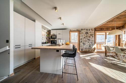 une cuisine avec des armoires blanches et une table et des chaises dans l'établissement Chalet Floquet de Neu Les Gets- BY EMERALD STAY, aux Gets