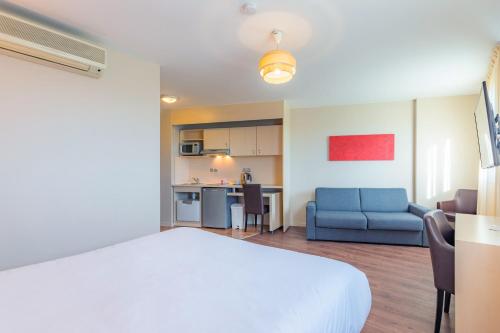 a room with a bed and a couch and a kitchen at Appart’City Confort Montpellier Ovalie I in Montpellier