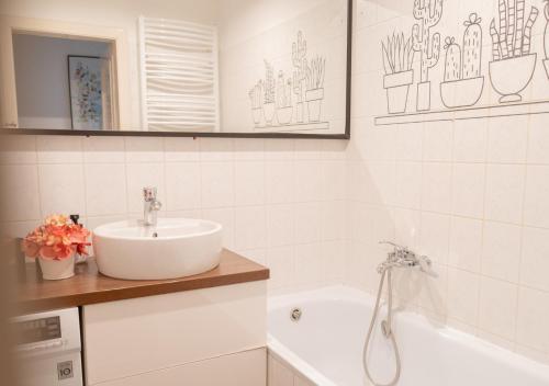 y baño blanco con lavabo y bañera. en Central Apartman, Belváros Lakás, en Kecskemét