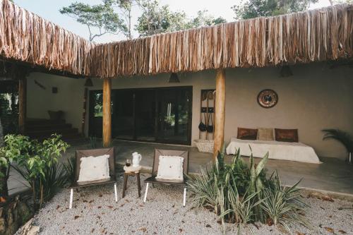 a bedroom with a bed and two chairs at CASA SUKHA Hotel in Trancoso