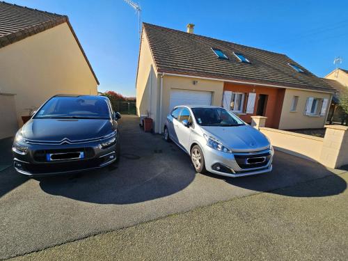 zwei Autos, die vor einem Haus geparkt sind in der Unterkunft Circuit du Mans Jacques Brel in Guécélard