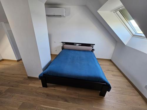 ein Schlafzimmer mit einem blauen Bett im Dachgeschoss in der Unterkunft Circuit du Mans Jacques Brel in Guécélard