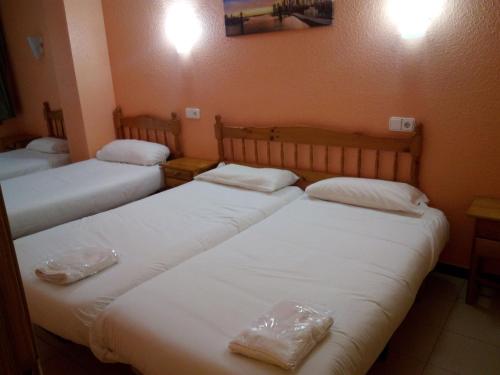 três camas num quarto com lençóis brancos em Apartaments Els Avets em Pas de la Casa