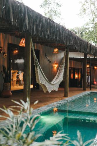 a hammock hanging from a house with a swimming pool at CASA SUKHA Hotel in Trancoso
