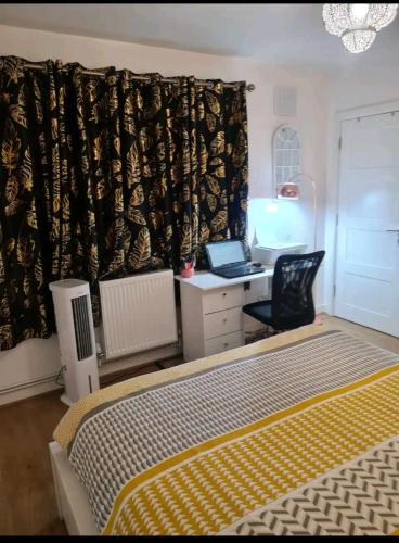 1 dormitorio con 1 cama y escritorio con ordenador portátil en Babus International, en Cranford