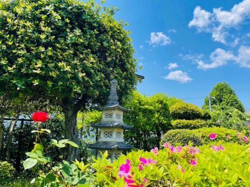 a statue in the middle of a garden with flowers at Shiga Biwa Lake Shanshui House in Takashima