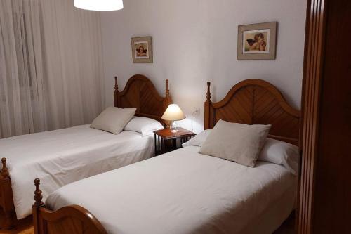La Casona de Teo في San Juan de la Arena: سريرين في غرفة الفندق ذات شراشف بيضاء
