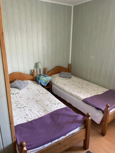 two beds in a small room with purple sheets at Pod daglezją in Bronków