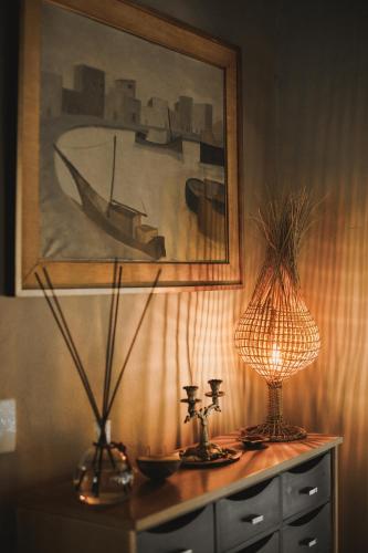 a table with a lamp and a painting on the wall at CASA SUKHA Hotel in Trancoso