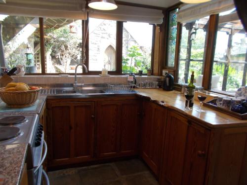 a kitchen with wooden cabinets and a sink and windows at Spindle Cottage 