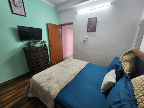 a bedroom with a blue bed and a television at Homlee-Best Value flat with kitchen Near Metro in New Delhi