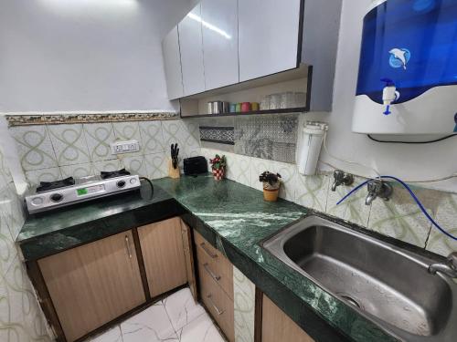 uma cozinha com um lavatório e uma bancada em Homlee-Best Value flat with kitchen Near Metro em Nova Deli