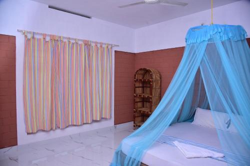 een slaapkamer met een bed met een blauwe baldakijn bij Doctors Ayurveda Heritage in Varkala