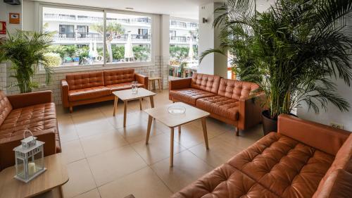 a waiting room with brown leather couches and tables at Coral California - Adults Only in Playa de las Americas